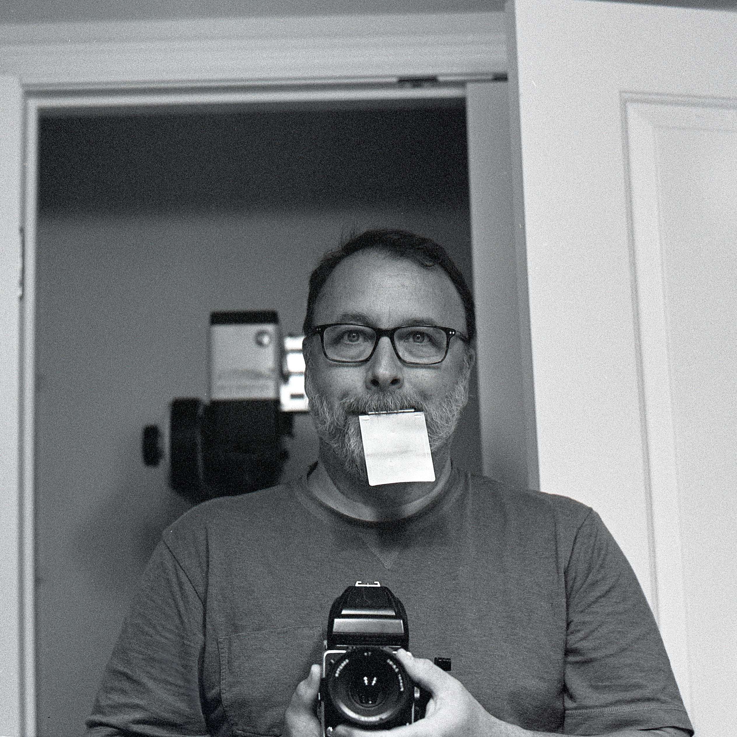 Self-portrait with the Hasselblad. Dark slide in mouth. Hasselblad 500C/M. Zeiss Planar 80mm f2.8. Tri-X